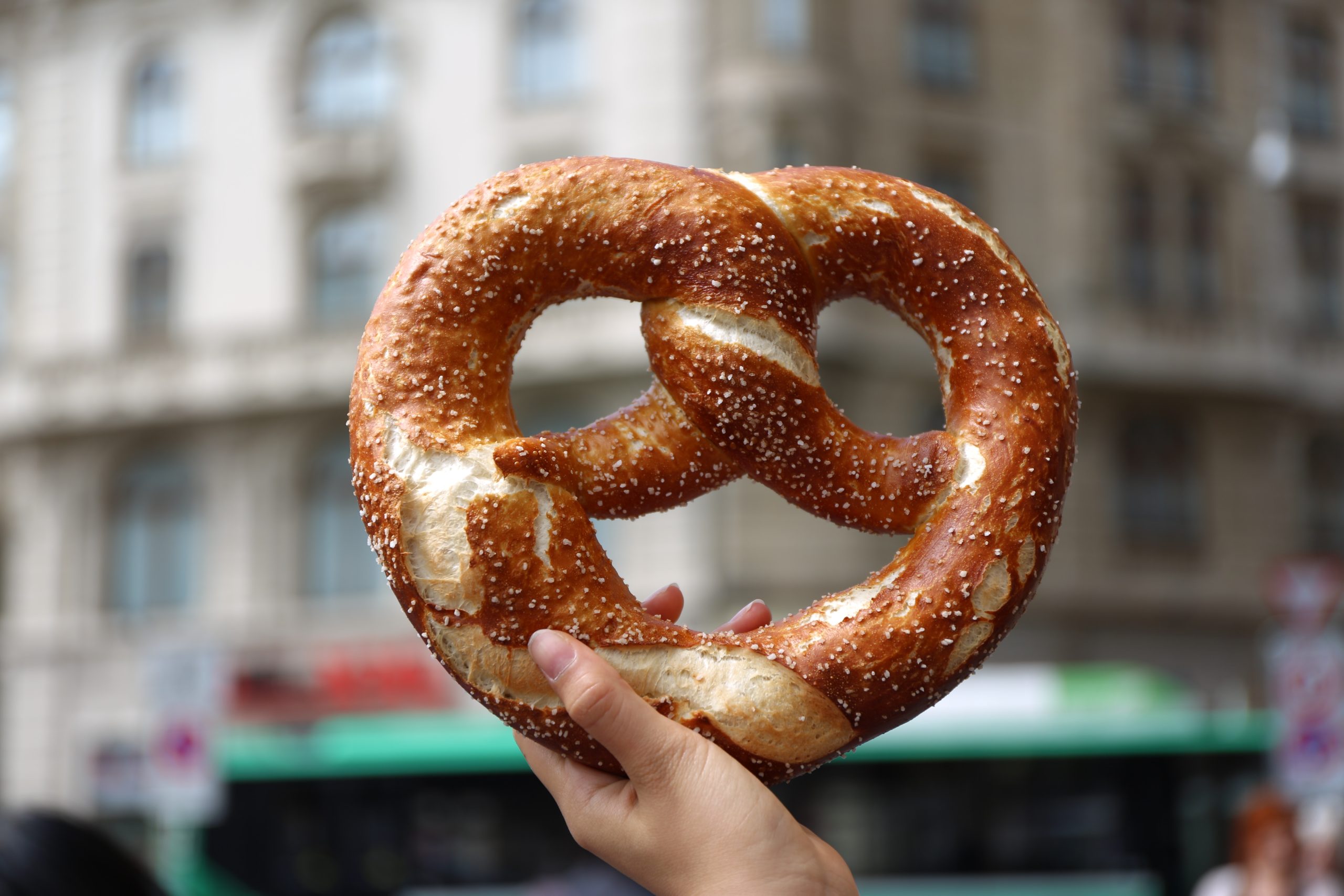 A hand holding a traditional German pretzel.
