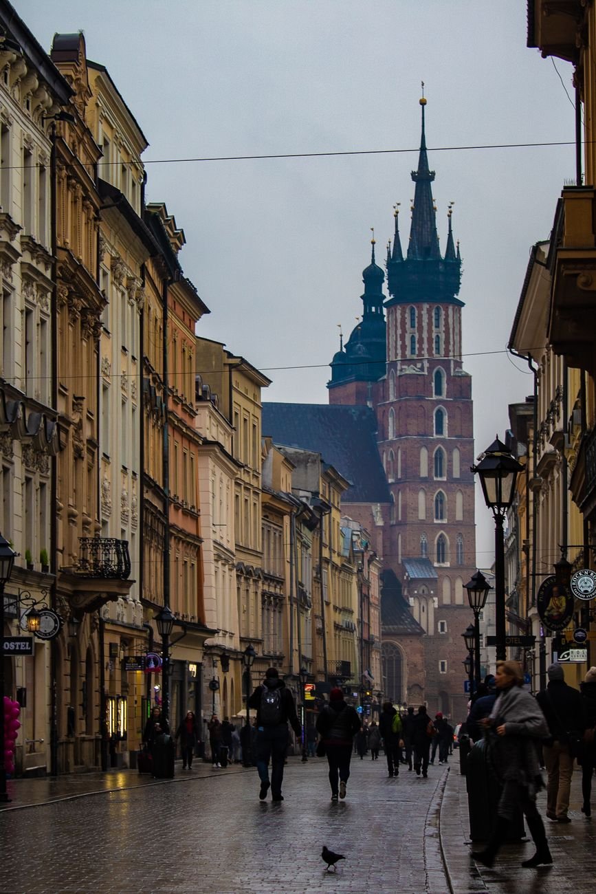 A cobblestone street in Kraków's Old Town with a gothic church tower ahead.