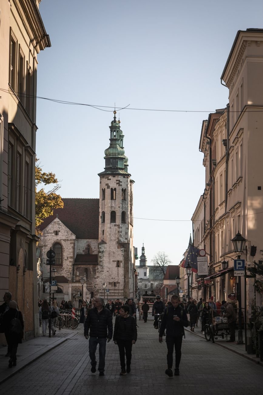 A cobblestone street lined with historic townhouses, a church spire visible ahead.