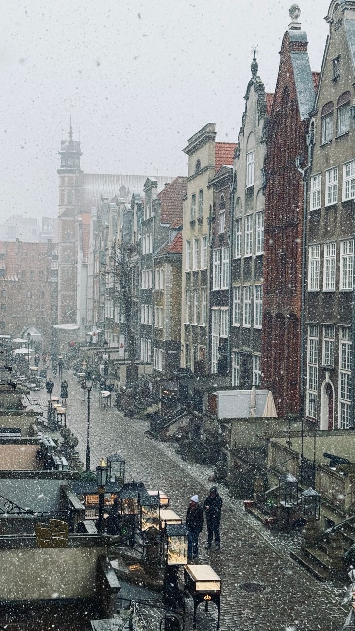 A snow-covered street lined with colorful merchant houses.