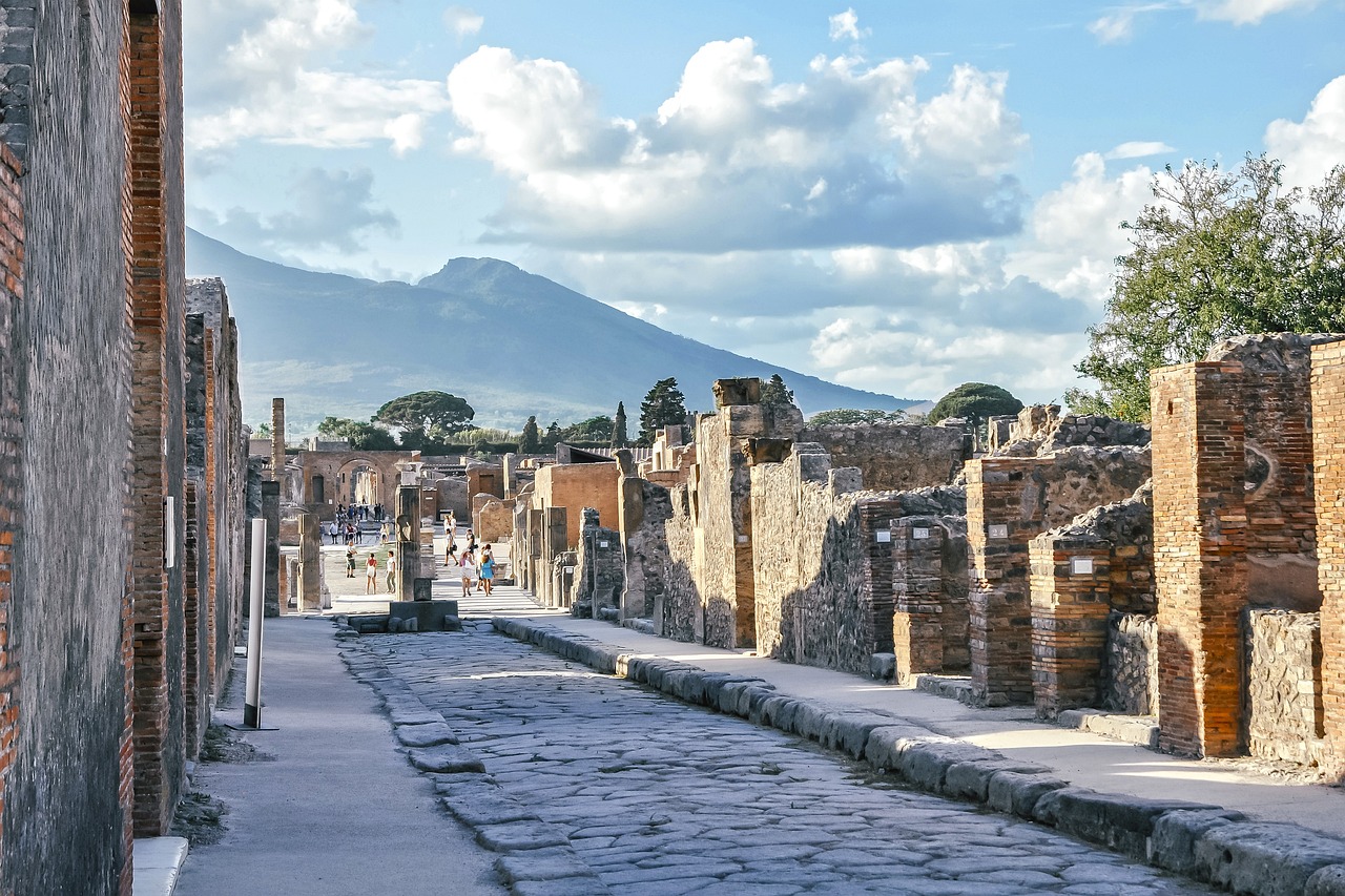 Ancient stone street runs through the ruins of Pompeii with Mount Vesuvius in the distance