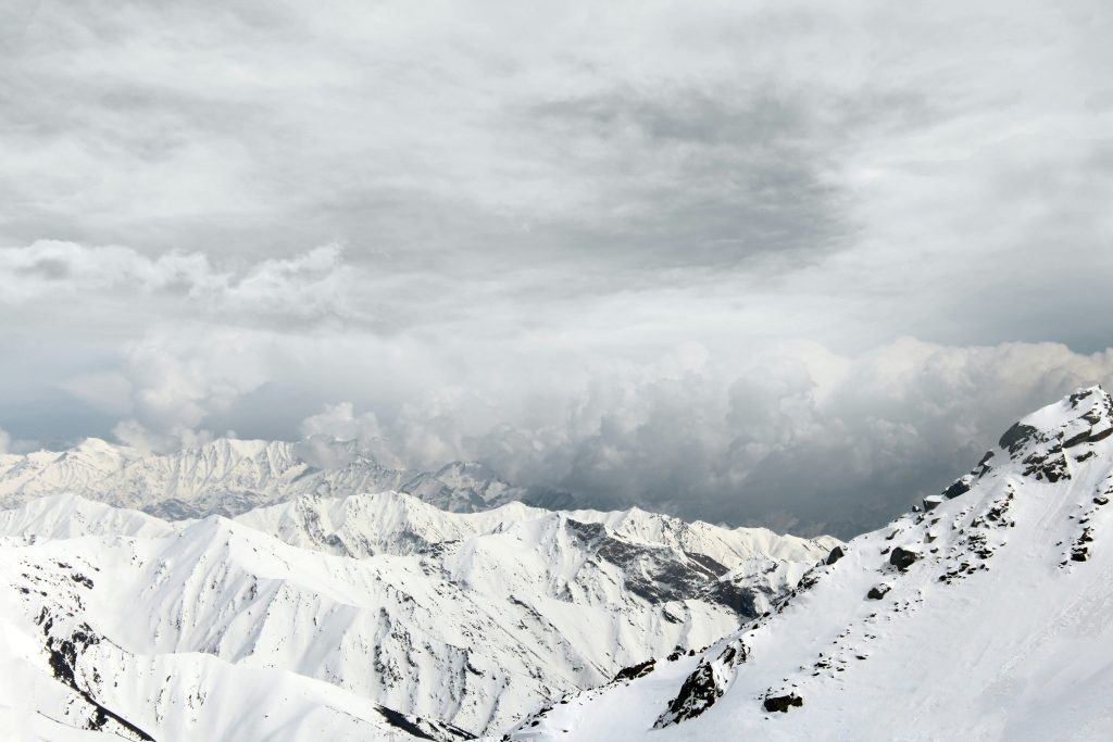 A panoramic view of snow-covered mountains under a cloudy sky.