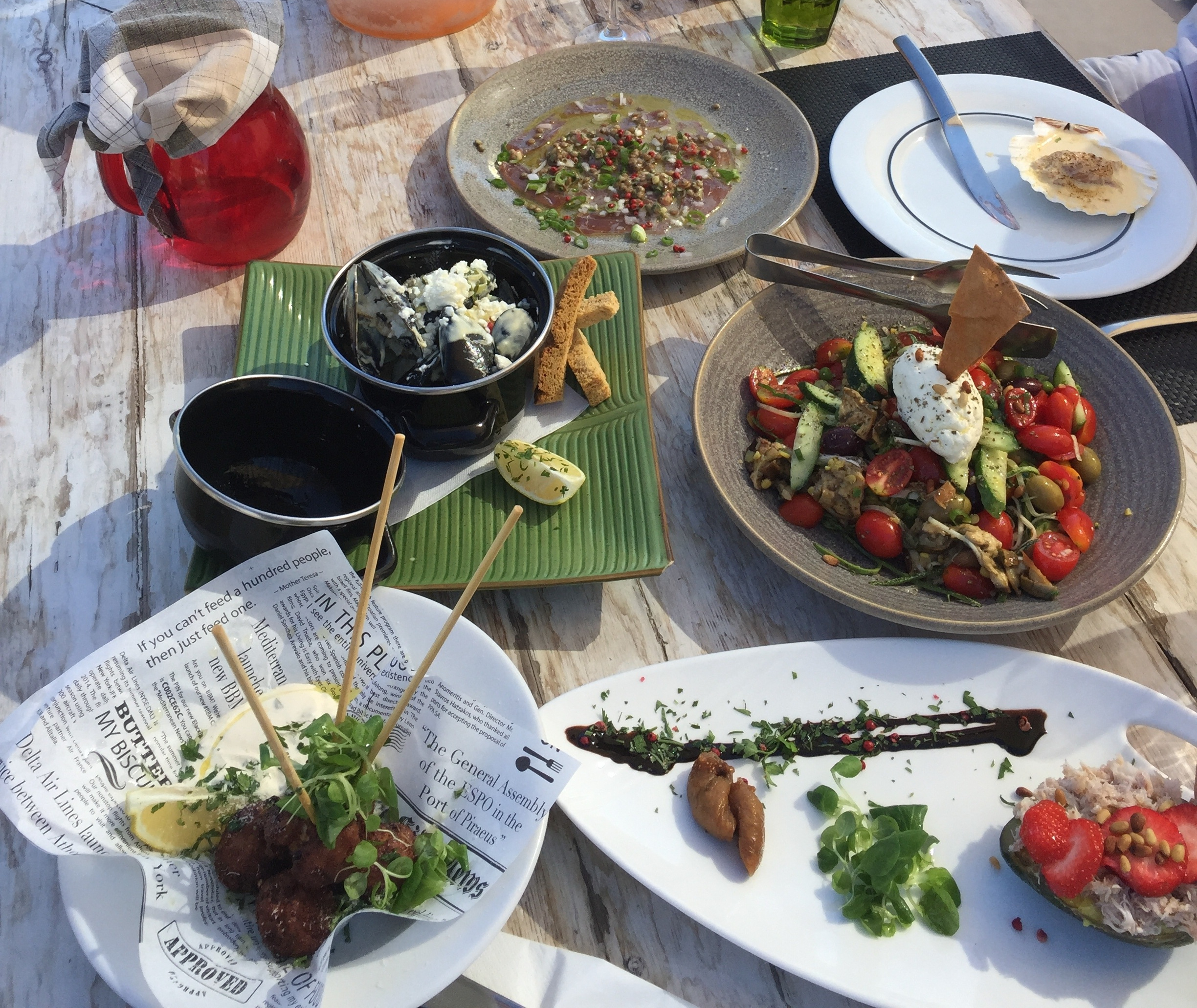 A table spread with Greek salads, seafood, and small plates