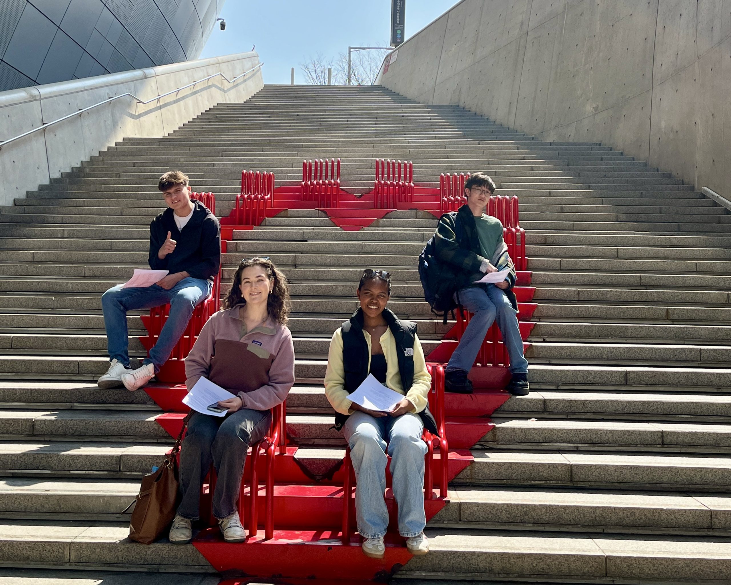 Students sit on red seating built into a large outdoor staircase in Seoul, in South Korea