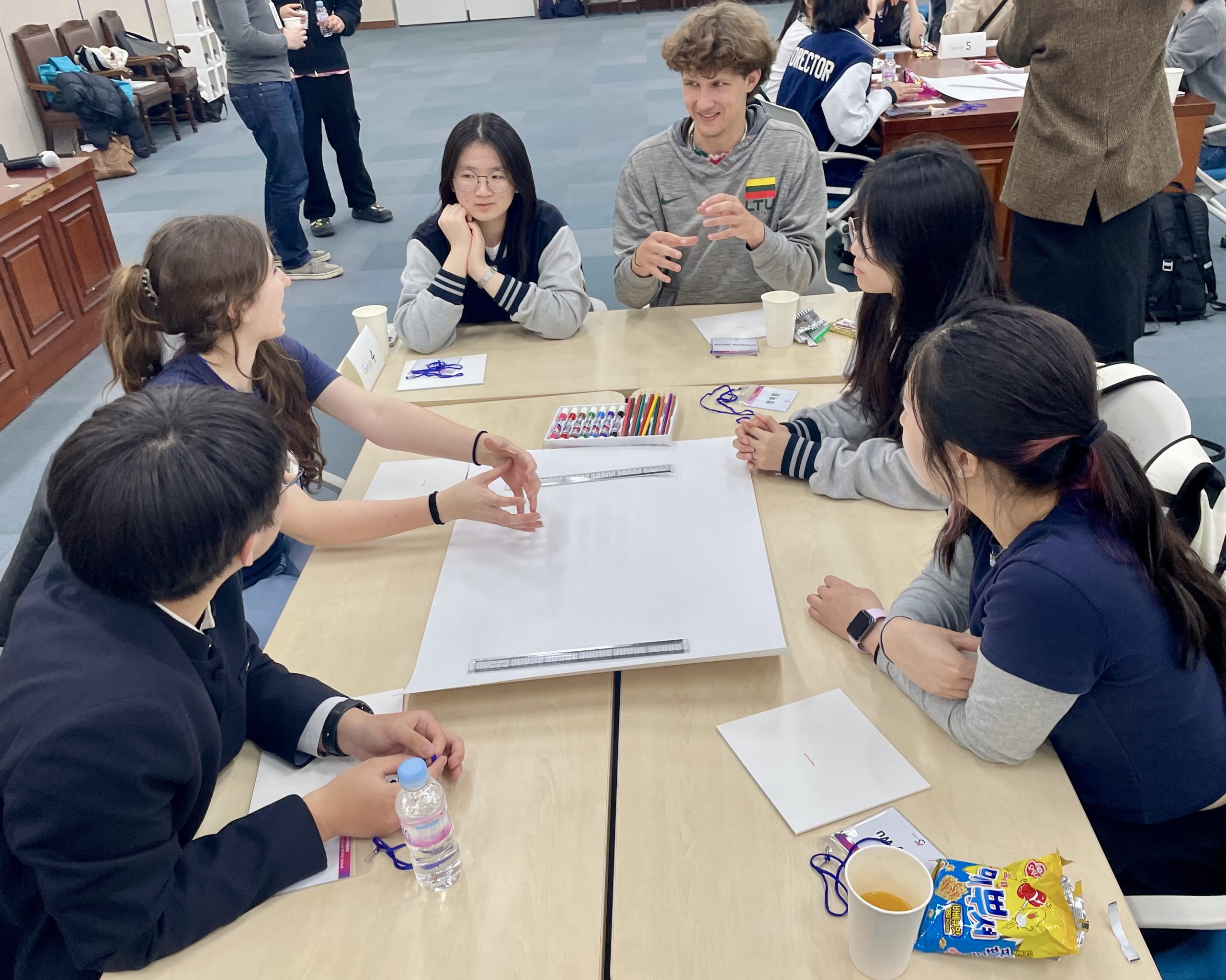 Rustic Pathways students and Korean students working together around a table on a group activity