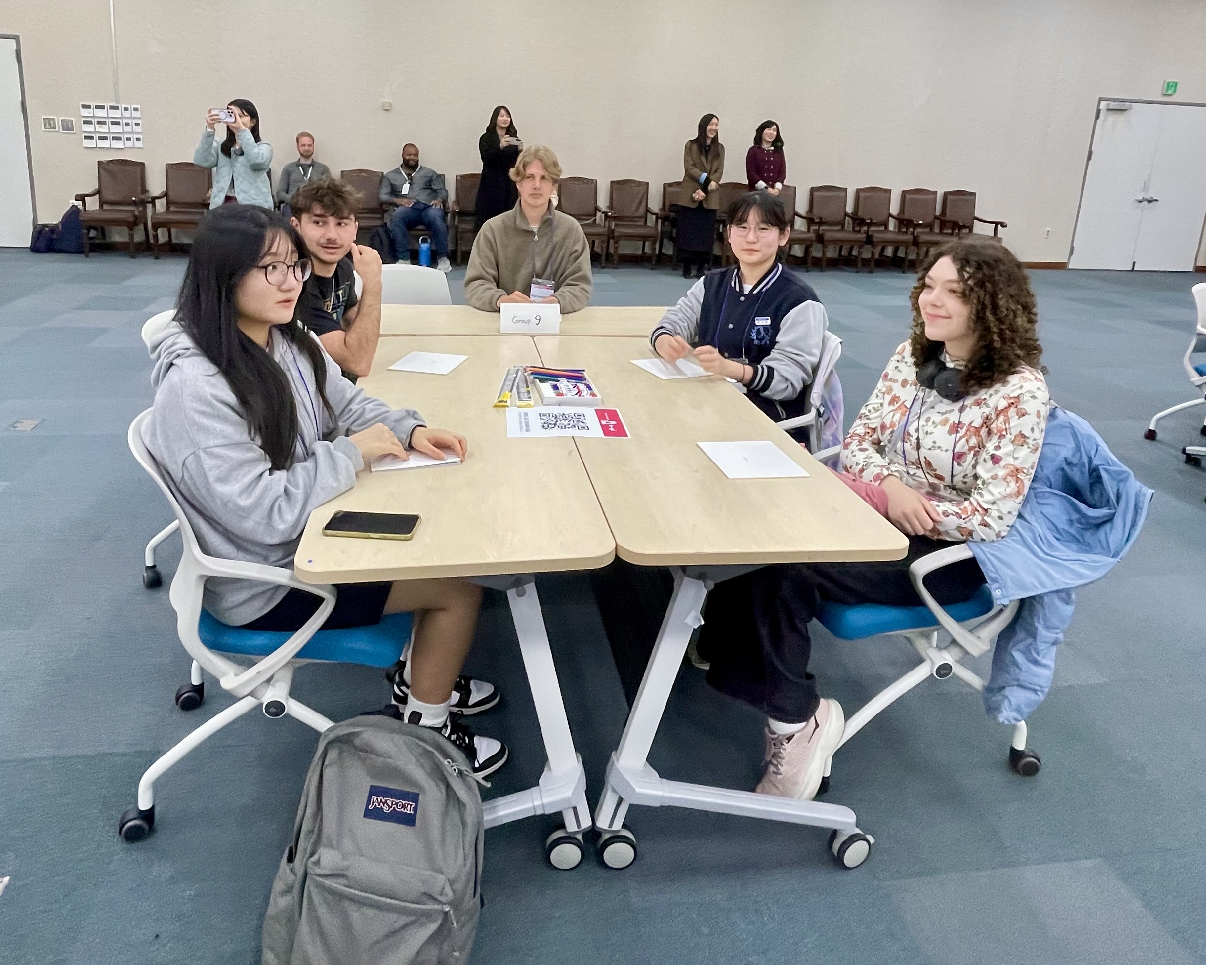 Students sit around a table in a conference room during a language exchange session