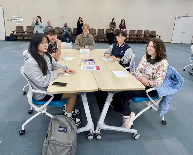 Students sit around a table in a meeting room during a language exchange session in Seoul