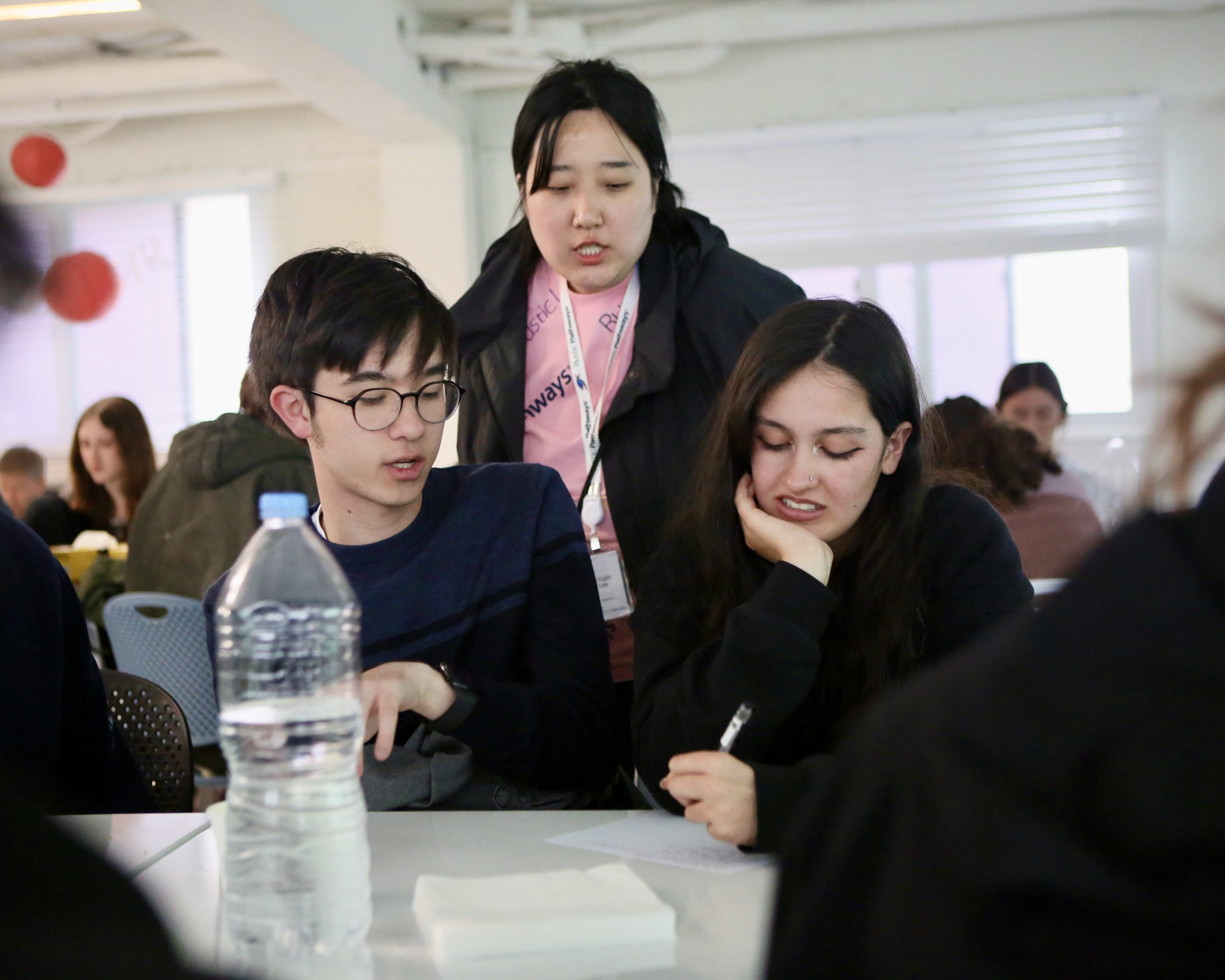 A Rustic Pathways leader helping two students during a classroom activity in Seoul