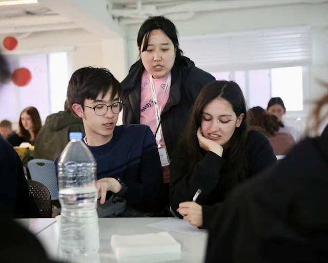 A Rustic Pathways leader helps two students with their work during a classroom session in Seoul