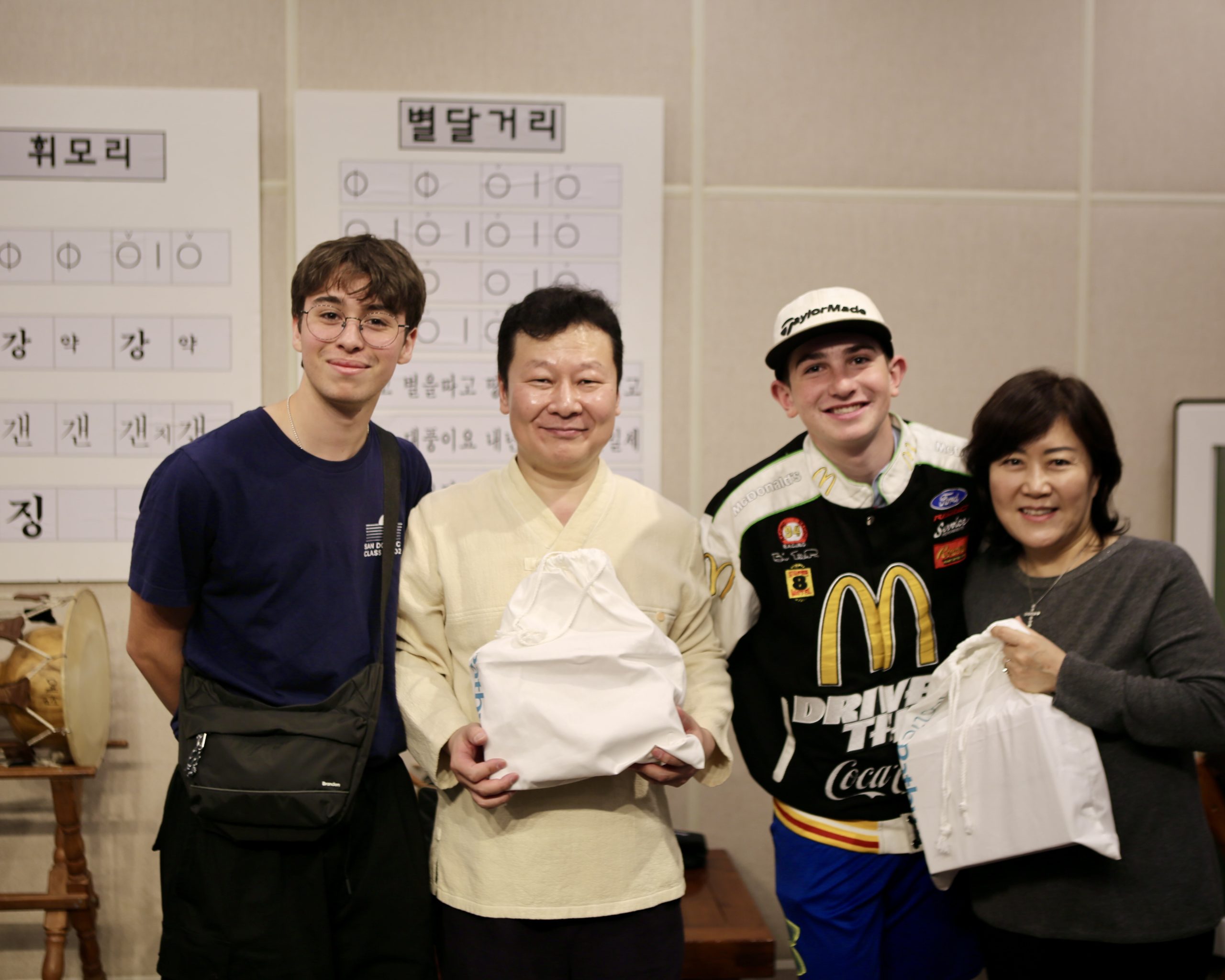Teen travelers pose with hosts holding wrapped gifts in a traditional classroom