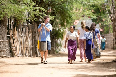 A student walks with local women during a service project in Thailand as part of a teen tour in Asia.