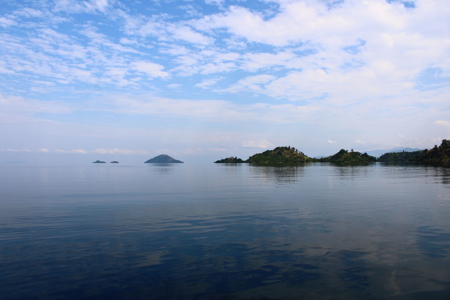 Small islands rising from the still water of a lake.