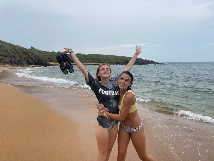Students raise their arms cheering on a beach in Puerto Rico