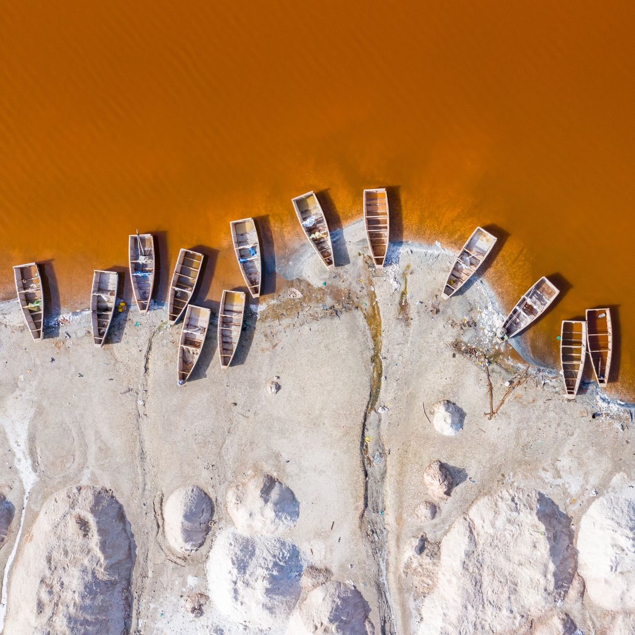 Small wooden boats moored on a sandy shore beside calm water.