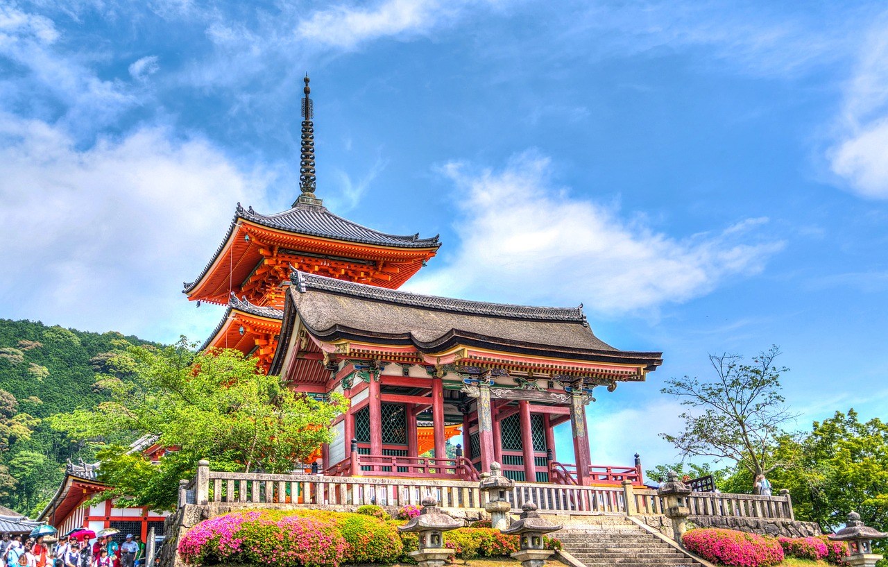 A red pagoda and temple hall surrounded by flowering shrubs on a hillside