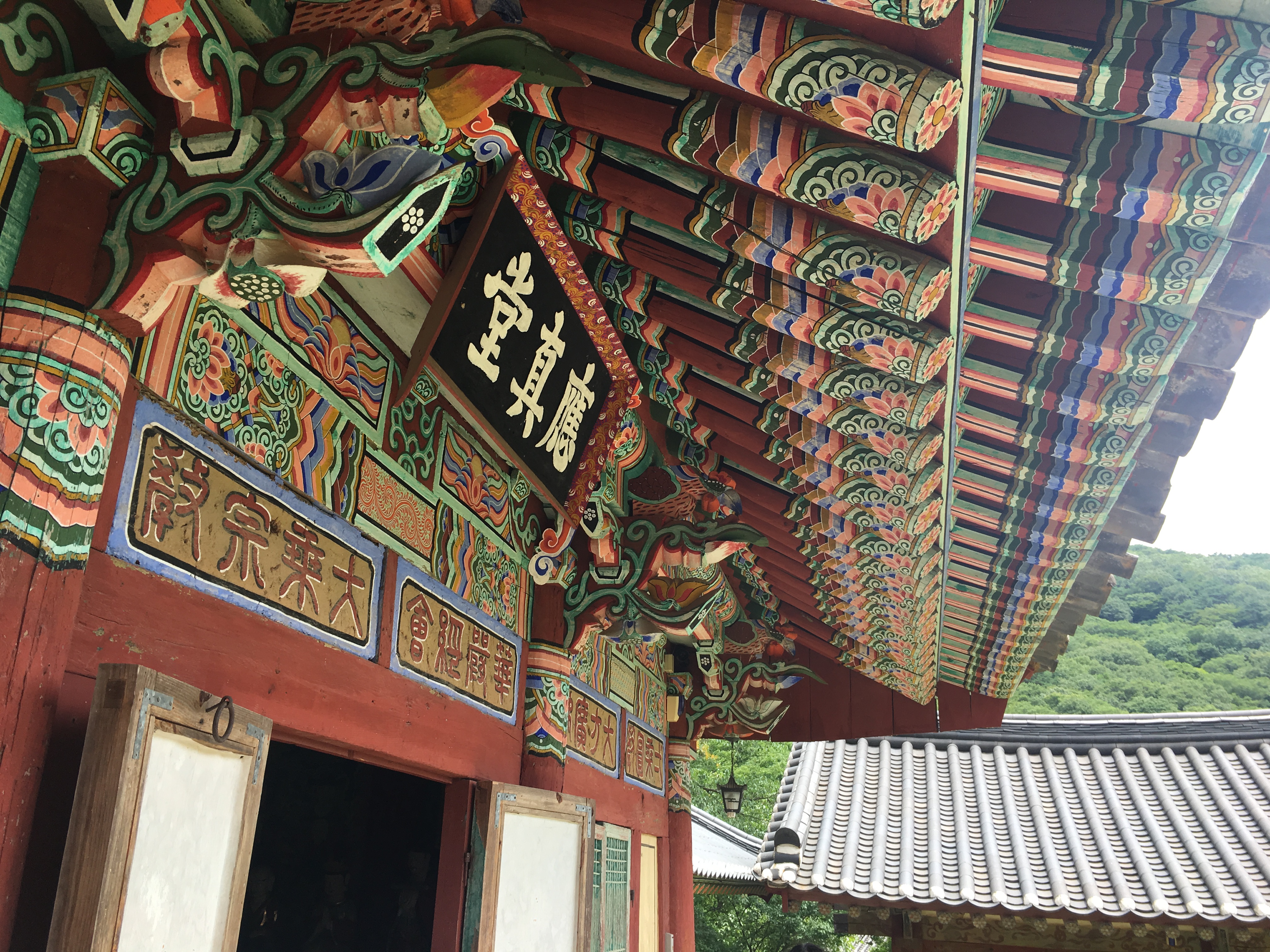 Ornate painted eaves and carved signage decorate a traditional Korean temple building
