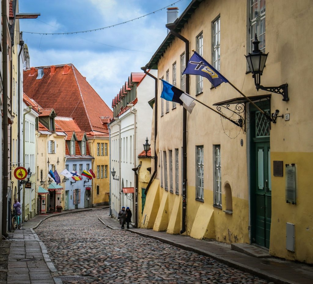A cobblestone street in Tallinn’s Old Town with colorful buildings and flags, showcasing the city’s walkability and charm.