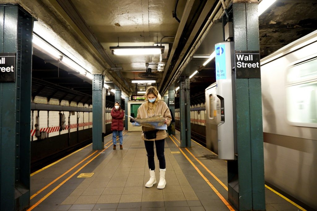 A woman stands at Wall Street Station in New York as a train speeds past.