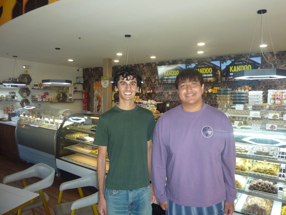 Shreyas Chatterjee and Roshan Saxena standing in front of the pastry cases at Kandoo Cafe and Custom Cakes