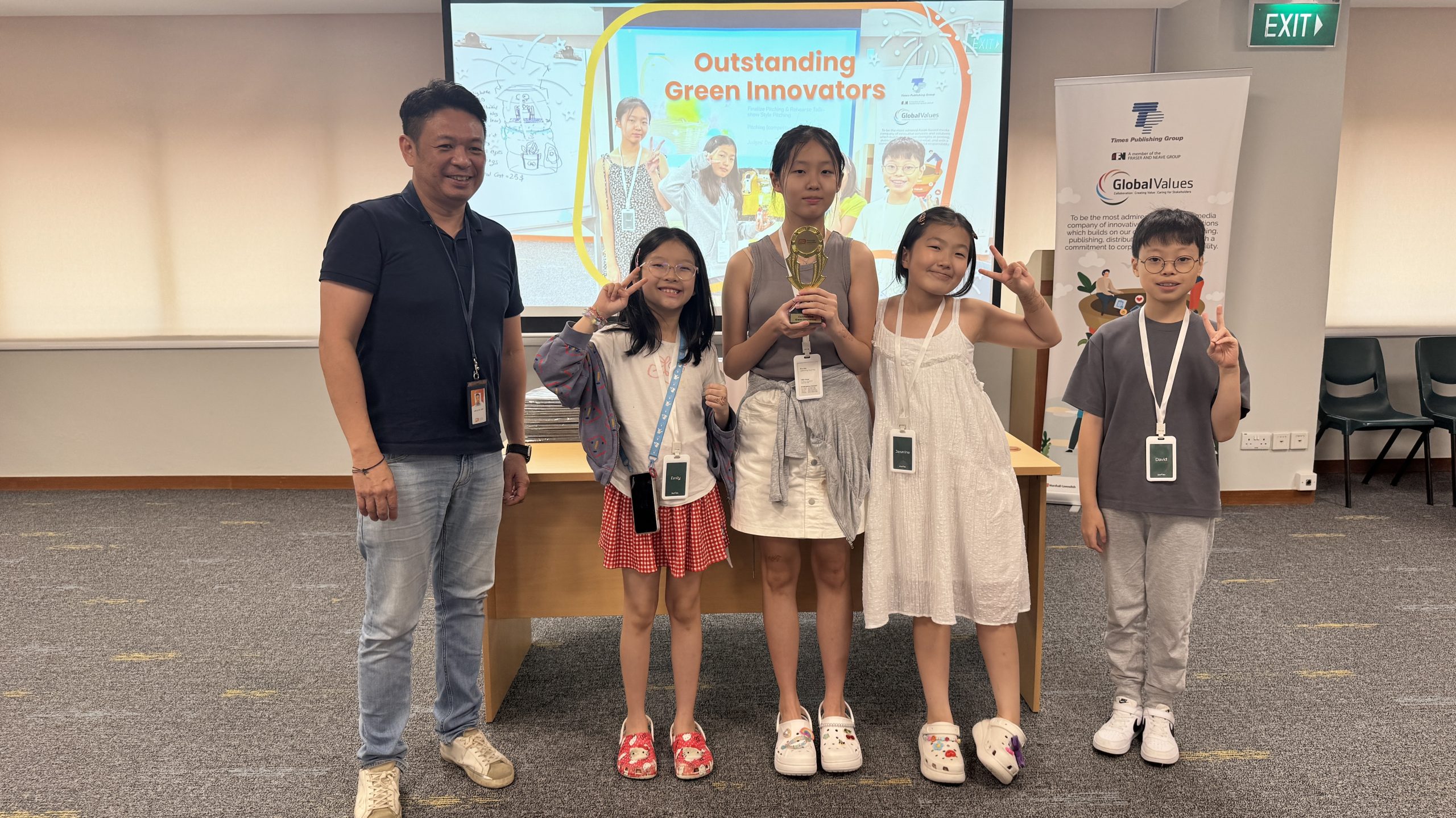 Students pose with a trophy beside an "Outstanding Green Innovators" presentation slide