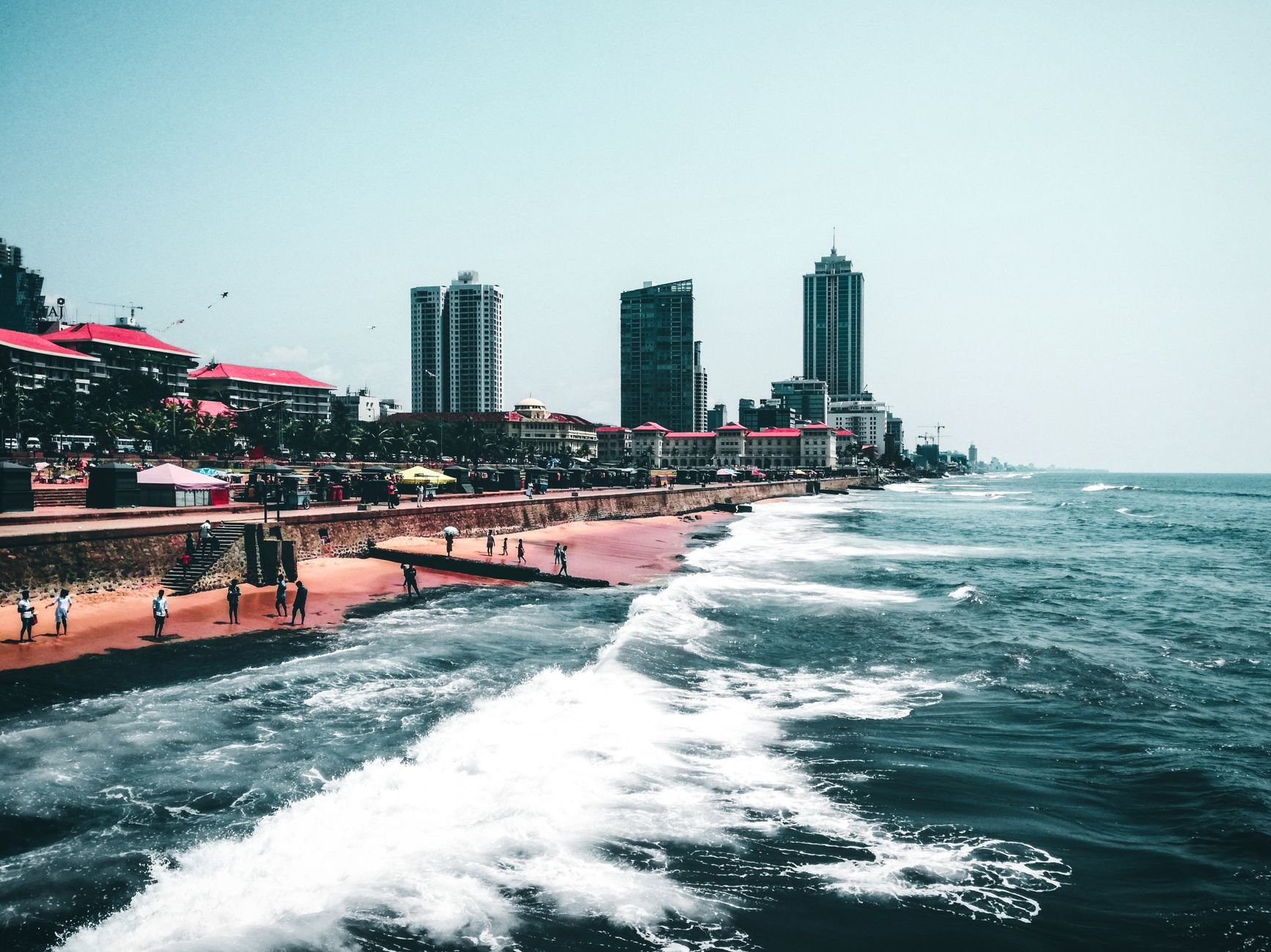 People walking along a beach as waves break at the shoreline.