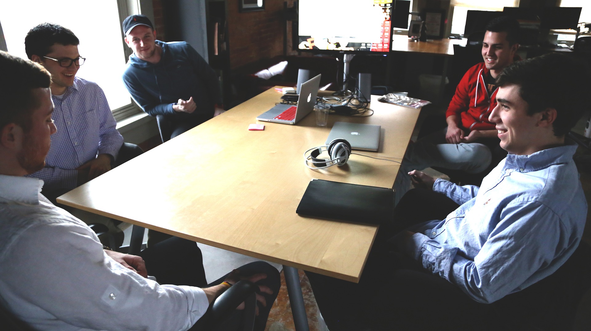 Students gather around a table with a laptop and headphones during a discussion
