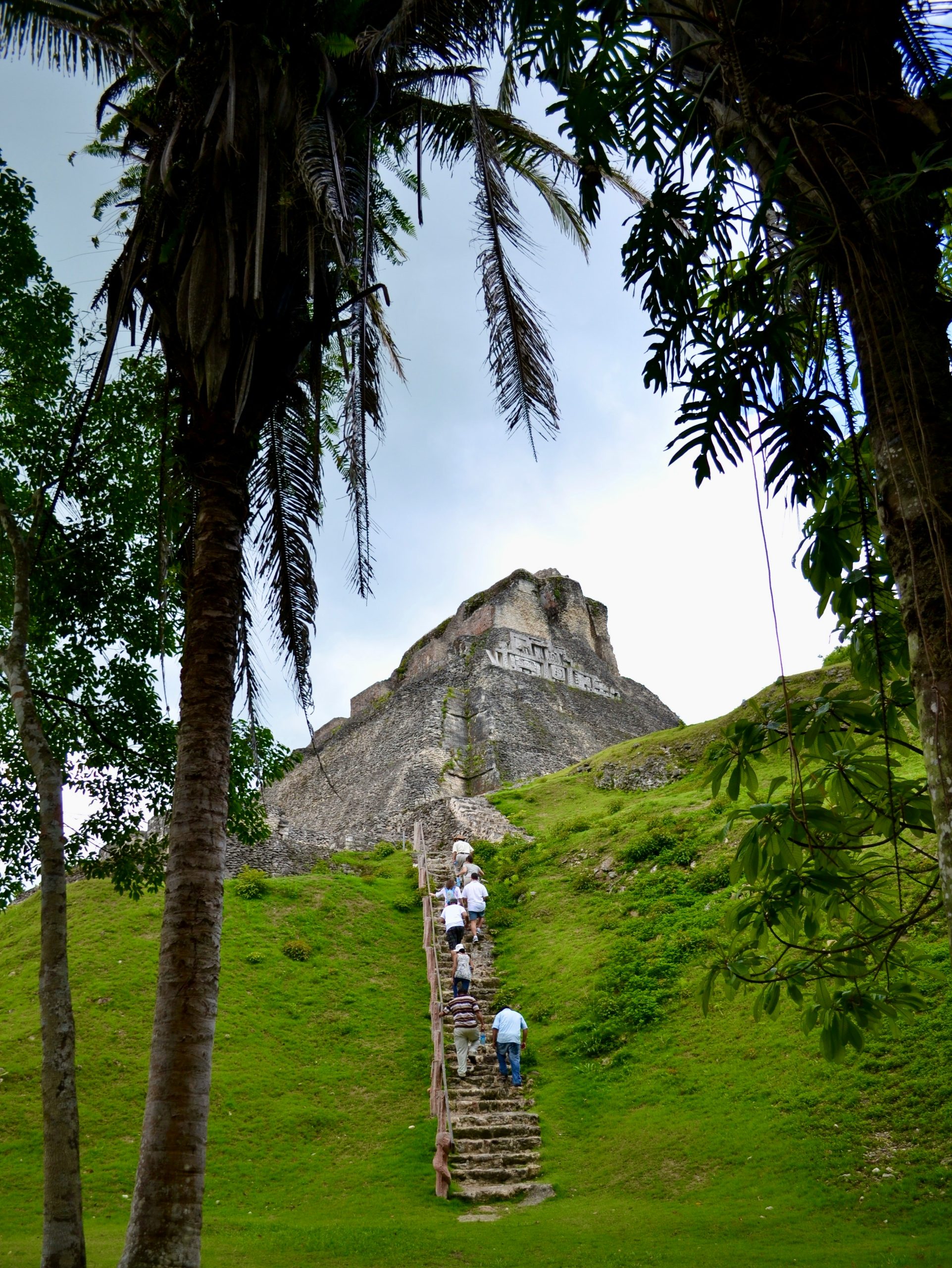Visitors climbing stone steps towards the top of an ancient Mayan ruin in Belize.