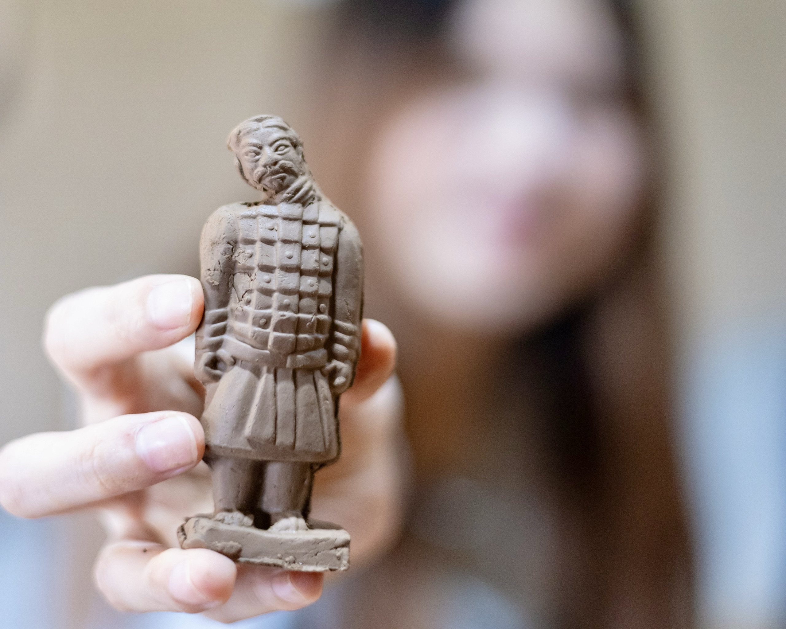 A student holding up the miniature terracotta warrior she sculpted with a craftsman in Xi'an, China