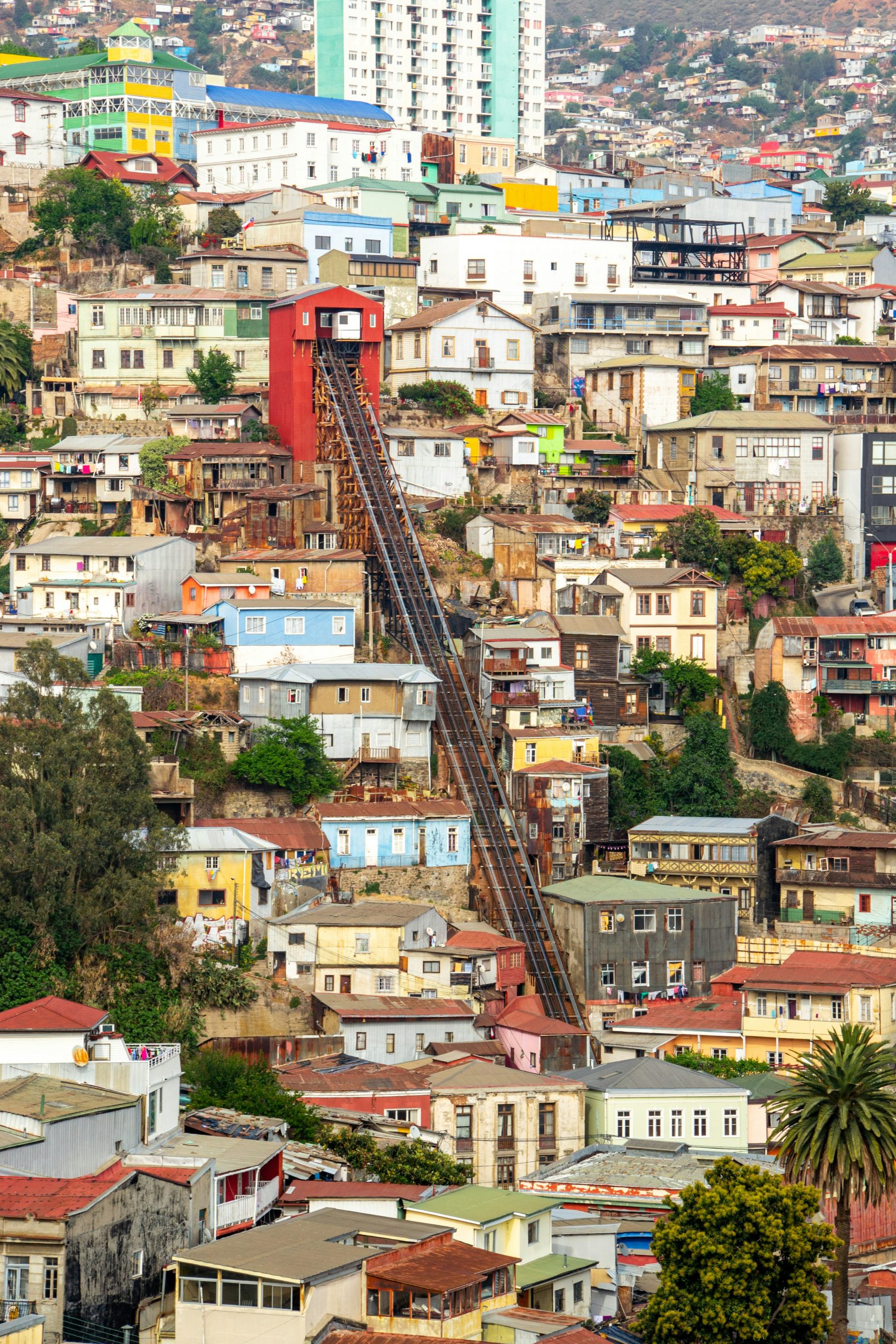 Teen travelers ride a funicular railway climbing a steep hillside packed with colorful houses in Valparaíso