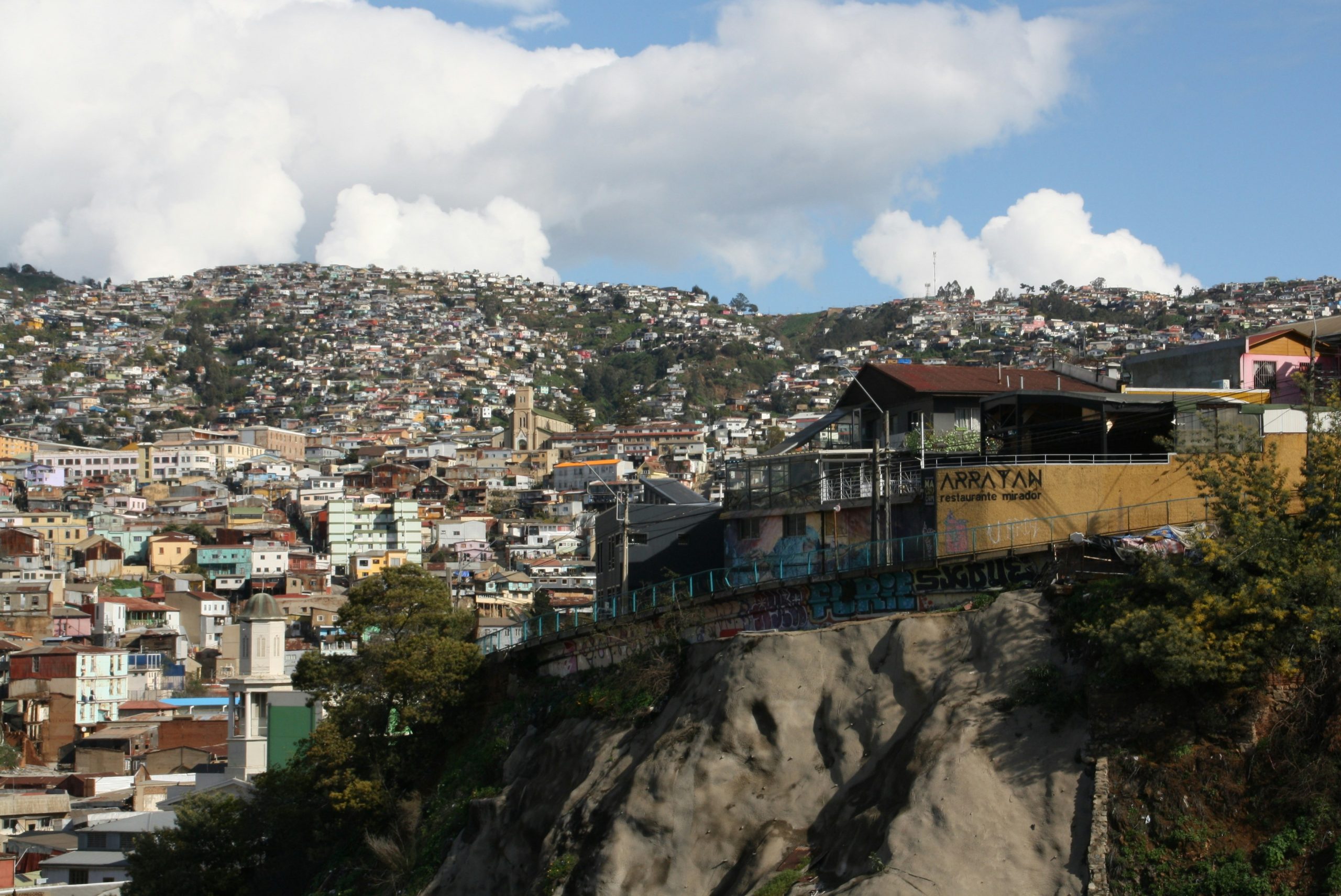Colorful hillside houses in Chile overlook a coastal Valparaíso neighborhood under a cloudy sky