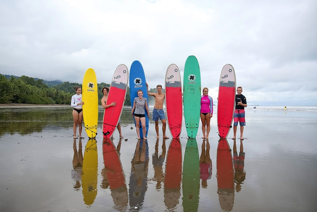 a group of students holding colorful surfboards during a surfing class on an outdoor program.