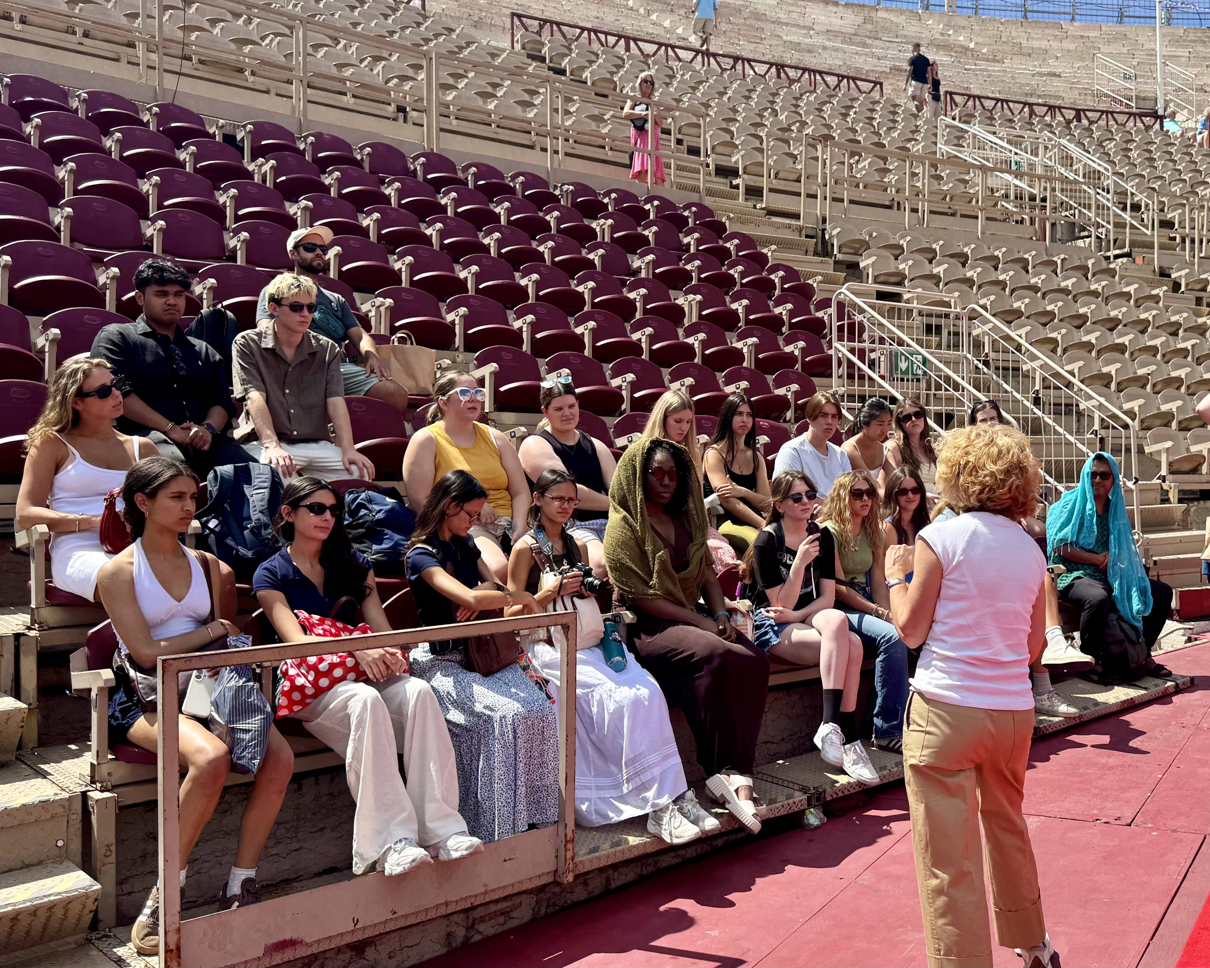 Rustic Pathways students seated in the stands of the Arena di Verona listening to a guided history lesson inside the ancient Roman amphitheater in Verona, Italy