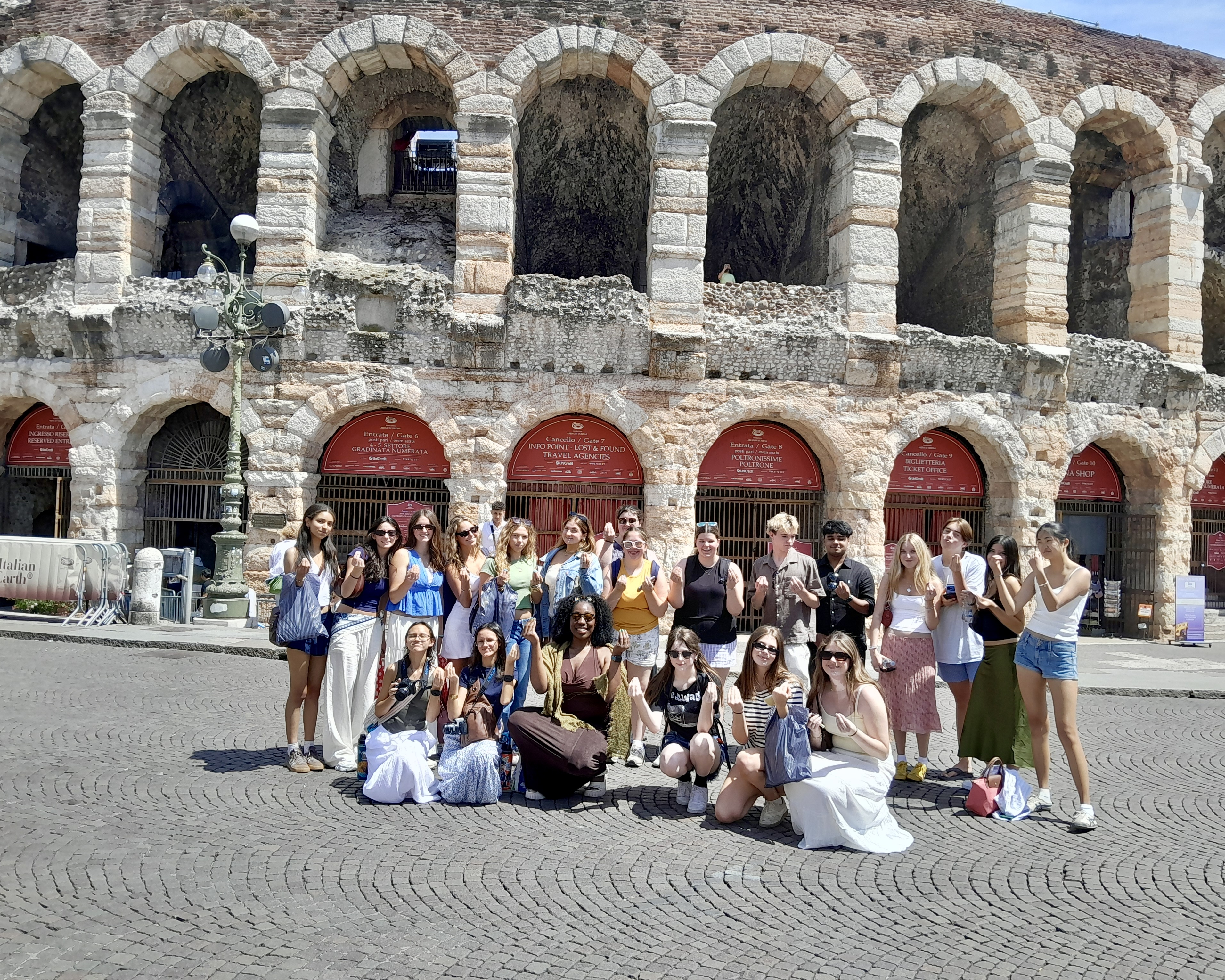The full Rustic Pathways Northern Italy Adventure group gathered on the cobblestone Piazza Bra in front of the arched stone facade of the Arena di Verona, Italy
