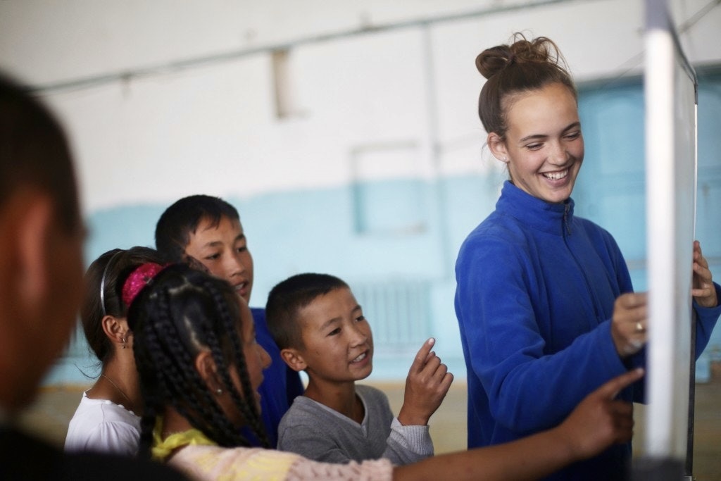 A summer program volunteer teaching local Mongolian schoolchildren at a whiteboard in a classroom