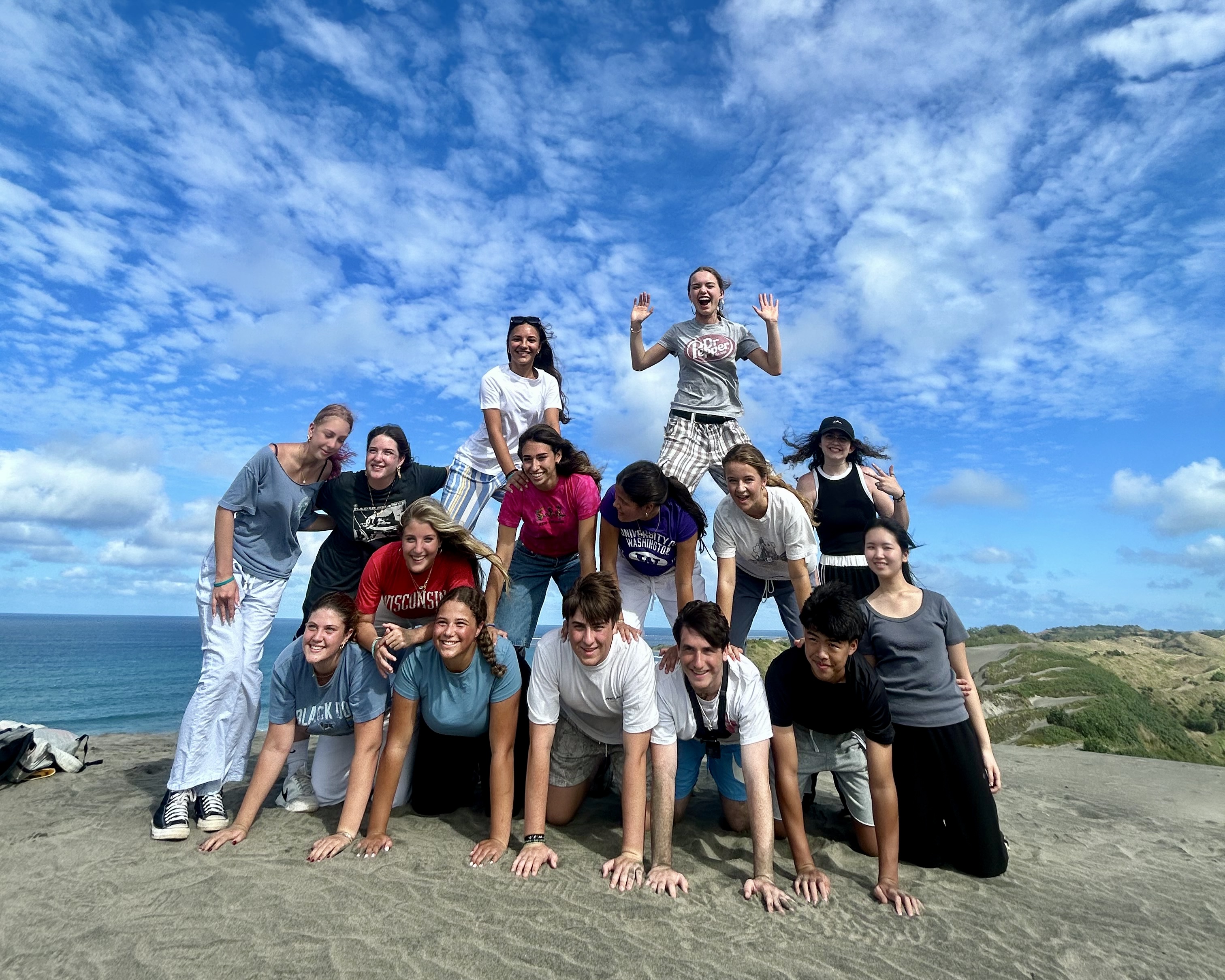High school students building a driftwood shelter on the beach with a local ranger in Fiji