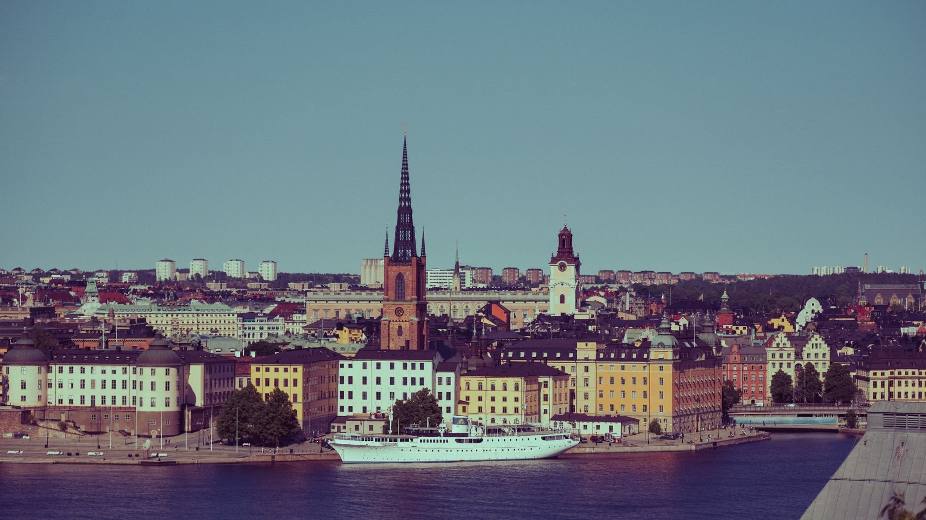 Riddarholmen Church rises above Stockholm's old town rooftops along the water.