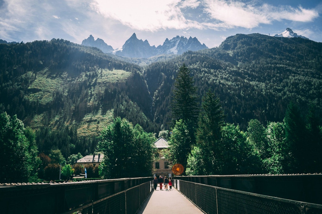 Landscape photo of forest and trail in the Swiss Alps with people walking on the trail.