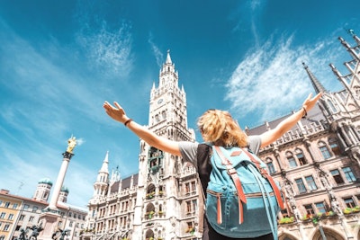 A female student raises her arms in celebration in a town square on a teen tour in Europe