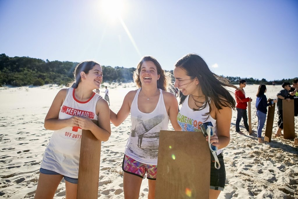 Rustic Pathways teen travelers laughing on the beach during a summer program for high school students in Australia.