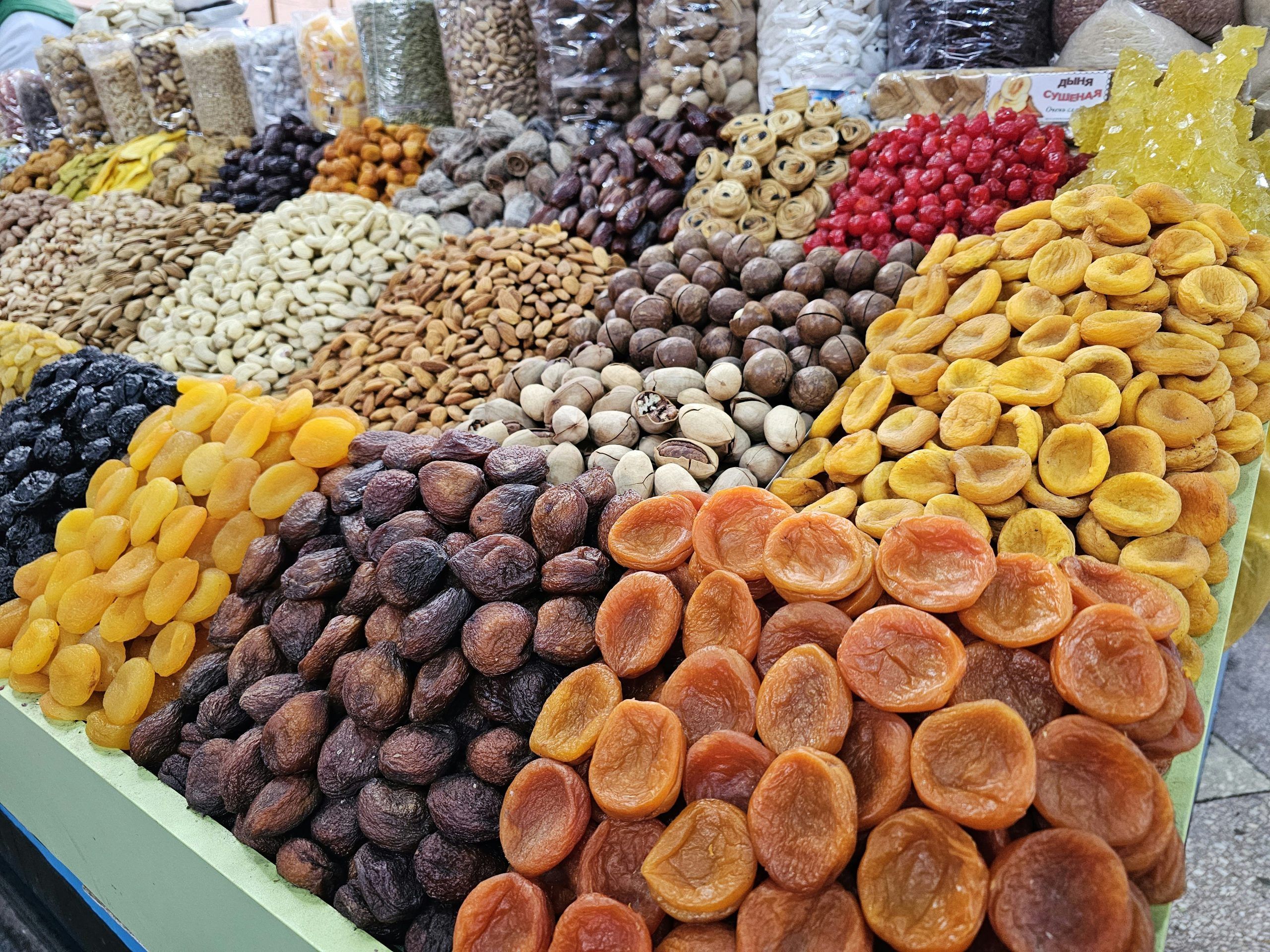 Piles of dried apricots, nuts, and raisins fill a market stall