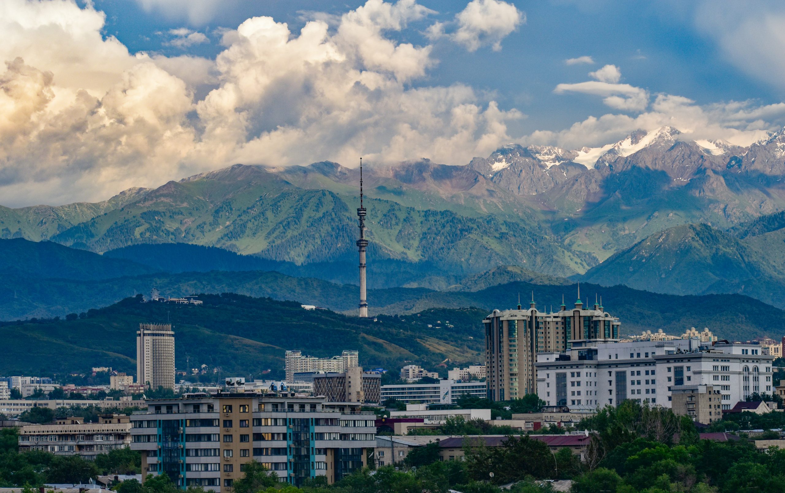 Snow-capped mountains rise behind Almaty's skyline of apartment towers and a television tower in Kazakhstan