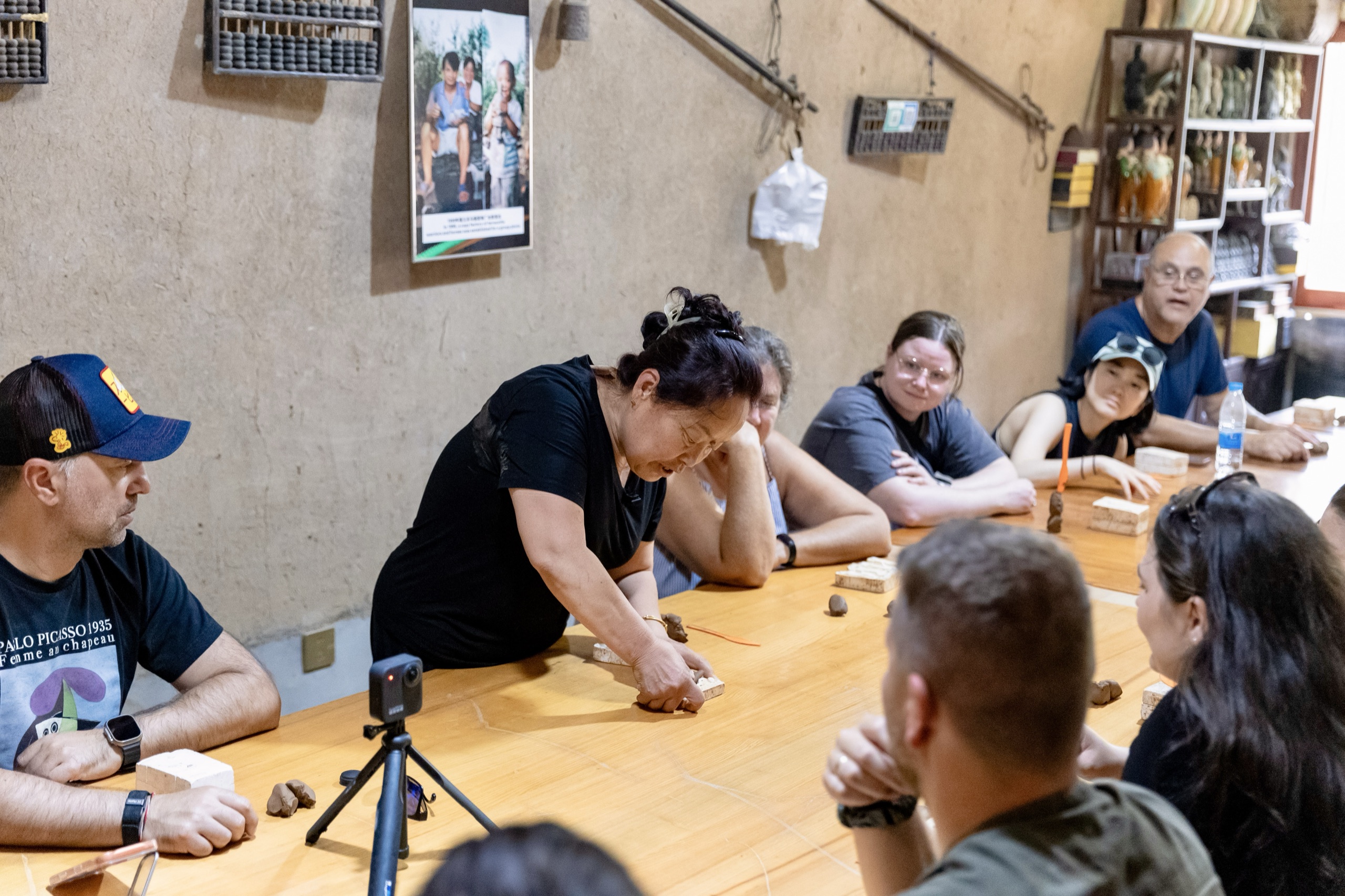 A local craftswoman in Xi'an, China demonstrating how to sculpt a miniature terracotta warrior to a seated group of travellers