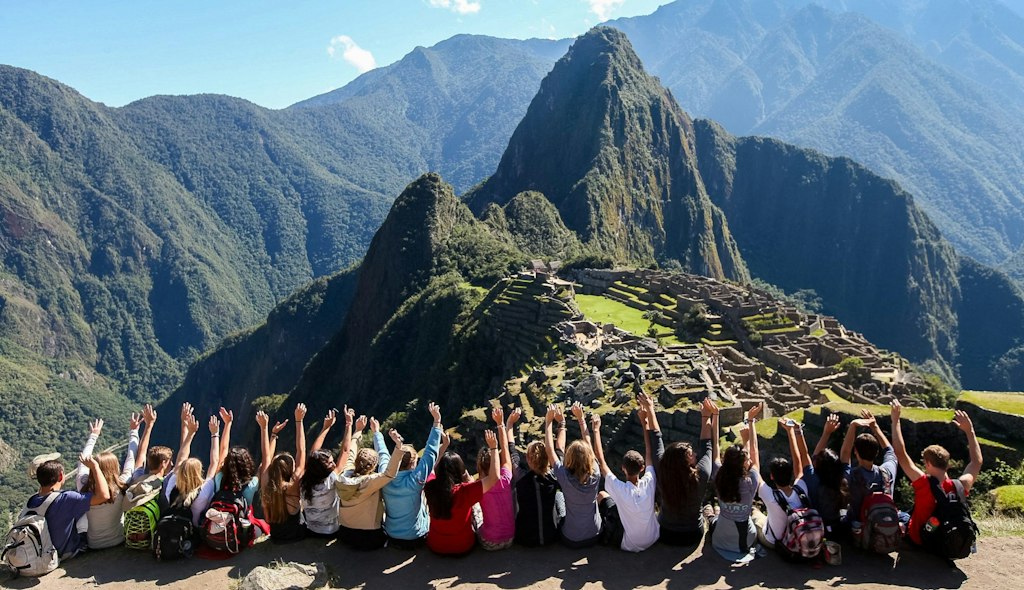 travel with teens teenagers in front of a mountain with their hands up