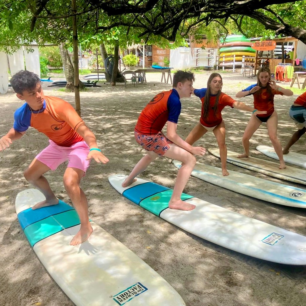 A travel with teens, we can see students learning how to surf while still on the sand