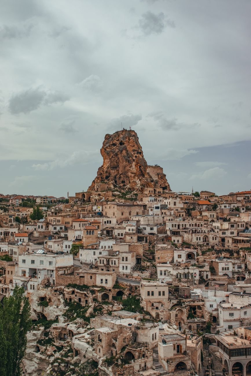 An aerial view of a rock-cut fortress rising above a town built into the cliffs around it.