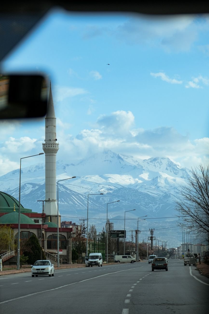A snow-covered volcanic peak behind a mosque minaret in winter.
