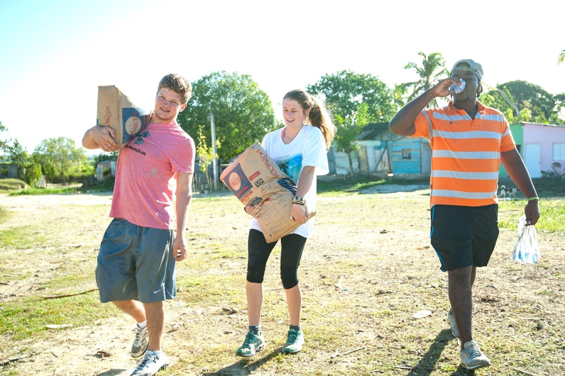 Volunteer service is one of the most impactful types of gap year programs, with students carrying supplies in a rural community