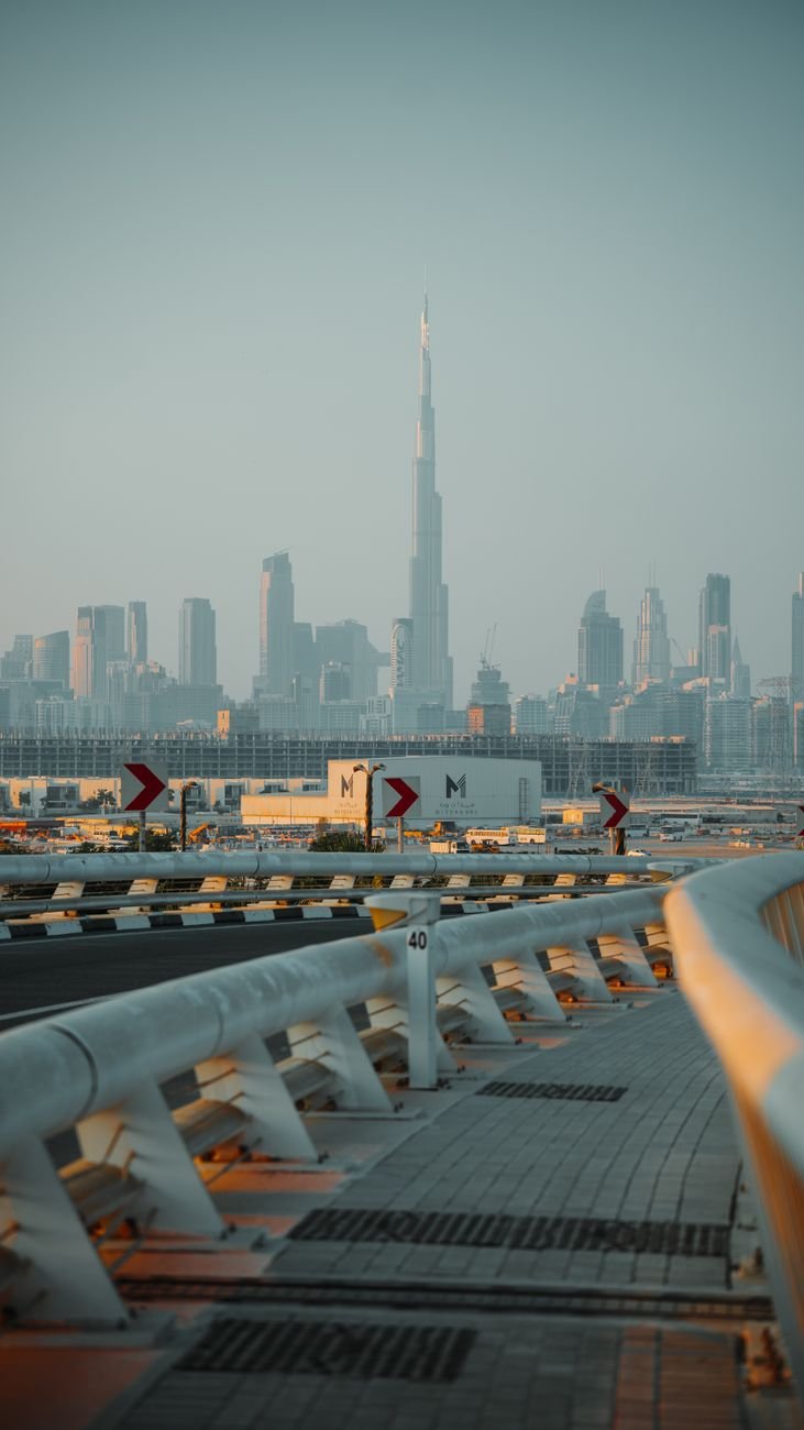 A highway curve with a distant tower rising above the skyline at dusk.