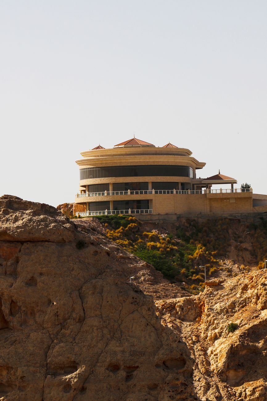 A round hilltop building perched above a rocky mountain slope.