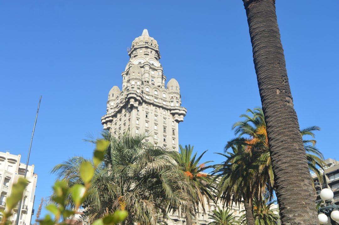 A landmark Art Deco tower rising above palm trees against a clear blue sky.